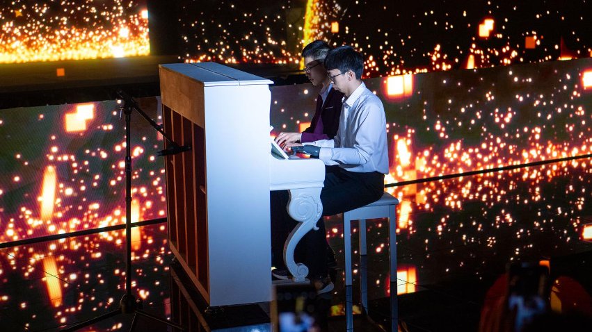 智能仿生手使用者古月與少年鋼琴家舒海峰合奏。主辦方供圖